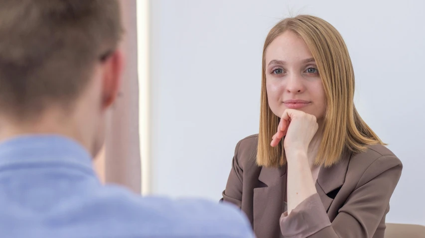 a woman sitting at a table in front of a man, profile image, professional image, lachlan bailey, female in office dress