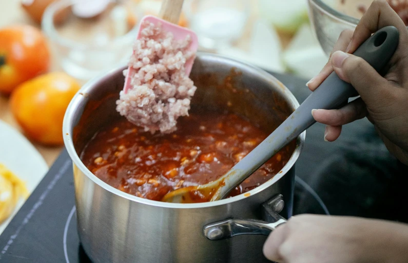 a person stirring food in a pot on a stove, by Julia Pishtar, pexels contest winner, process art, ground meat, square, holding hot sauce, pastel'