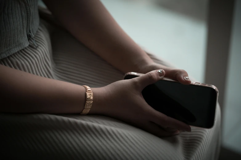 a close up of a person holding a cell phone, inspired by Nan Goldin, aestheticism, gold bracelet, resting, monochrome, gold