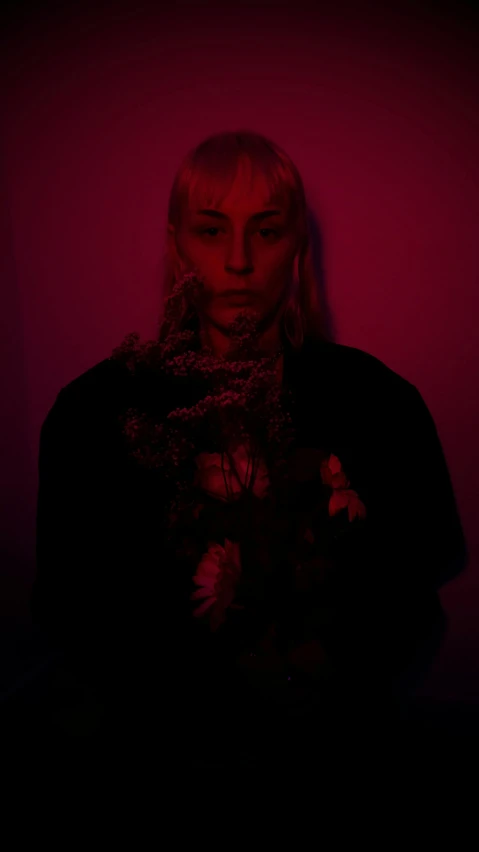 a woman standing in front of a red light, an album cover, inspired by Elsa Bleda, dark flower shaman, johan liebert, portrait n - 9, low quality photo