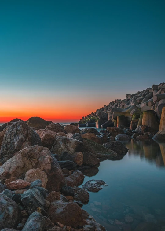 a large body of water surrounded by rocks, a picture, unsplash contest winner, romanticism, sunset colors, rock columns, ultrawide lens”, harbor