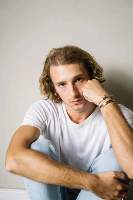 a man sitting in front of a laptop computer, an album cover, inspired by Sergei Sviatchenko, trending on unsplash, renaissance, curly dirty blonde hair, handsome young man, dressed in a white t-shirt, headshot