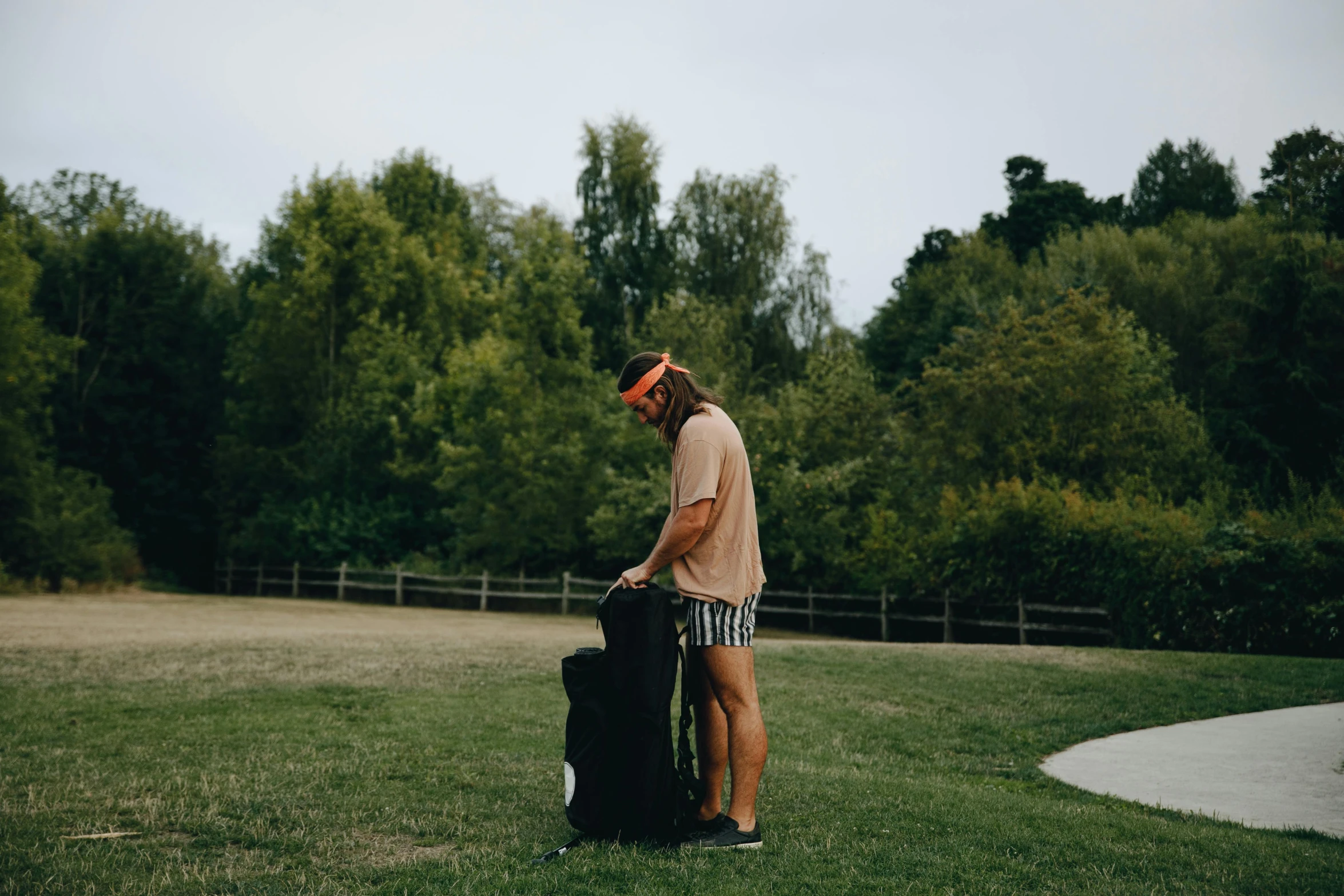 a man standing on top of a lush green field, an album cover, by Tom Bonson, pexels contest winner, happening, luggage, at a park, sup, lachlan bailey