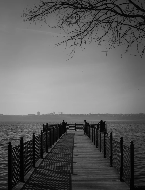 a black and white photo of a pier, by Tadeusz Makowski, city in the distance, fog. by greg rutkowski, michal mraz