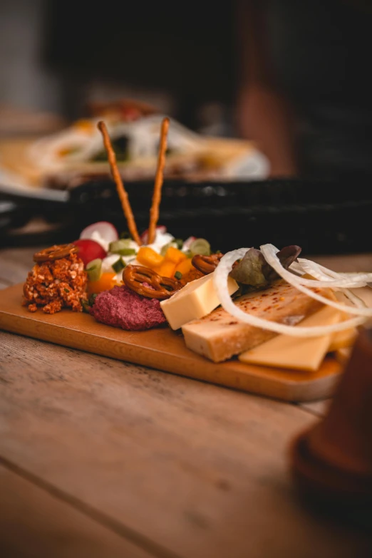 a wooden table topped with plates of food, by Andries Stock, pexels, made of cheese, woodfired, square, low detailed