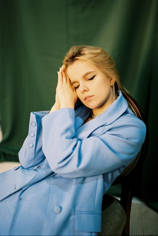 a woman in a blue coat sitting on a chair, looking tired, anya_taylor-joy, taken in the mid 2000s, wearing pajamas