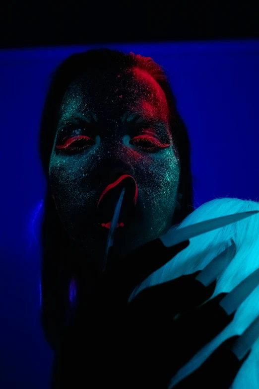 a woman holding a knife in front of her face, an album cover, inspired by Elsa Bleda, pexels contest winner, red and blue neon, psychedelic dust, fleshy creature above her mouth, nightlife