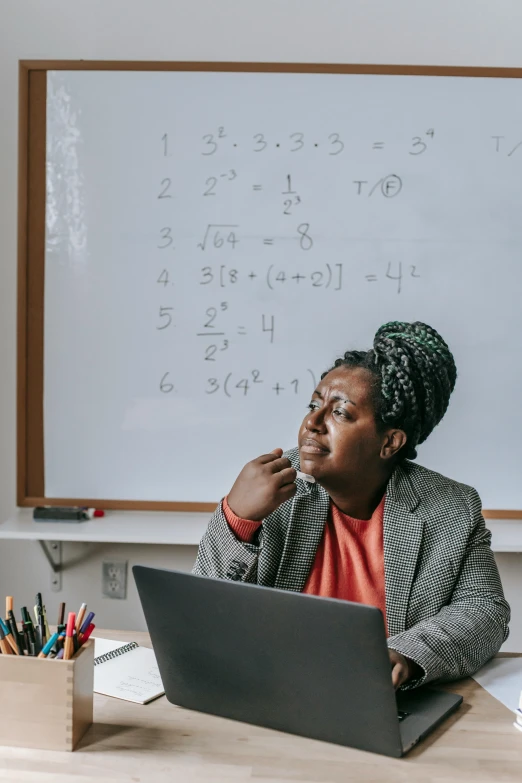 a woman sitting in front of a laptop computer, a picture, trending on unsplash, mathematics, in a school classroom, african canadian, background image