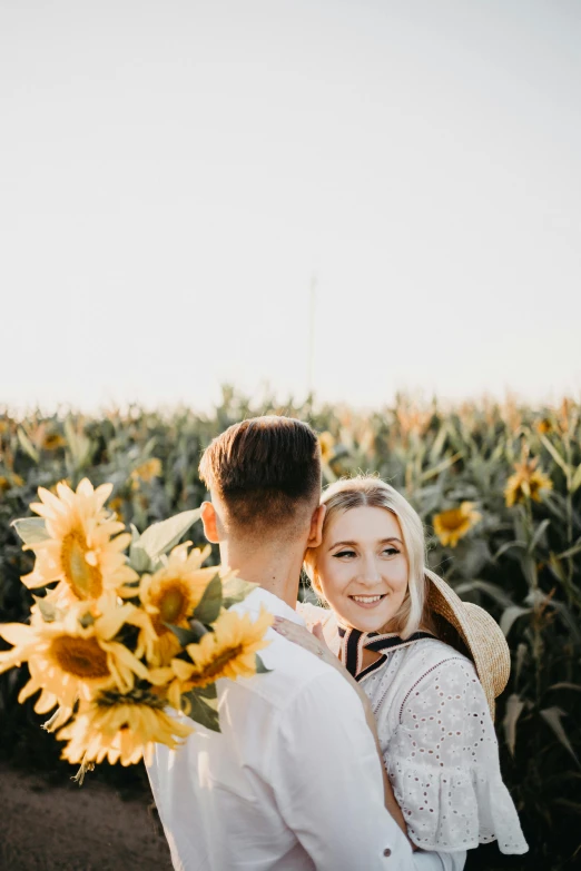 a man and woman standing in a field of sunflowers, pexels contest winner, flirting smiling, gif, centered in image, low quality photo