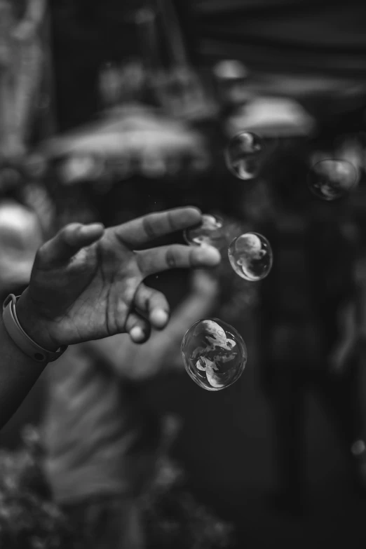 a black and white photo of a man blowing bubbles, by Adam Marczyński, pexels contest winner, hands up, simple, multiple stories, hand