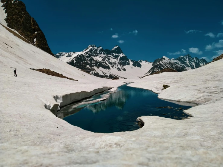 a man standing on top of a snow covered mountain, a tilt shift photo, pexels contest winner, hurufiyya, puddles of turquoise water, a photo of a lake on a sunny day, devils horns, sitting in a reflective pool