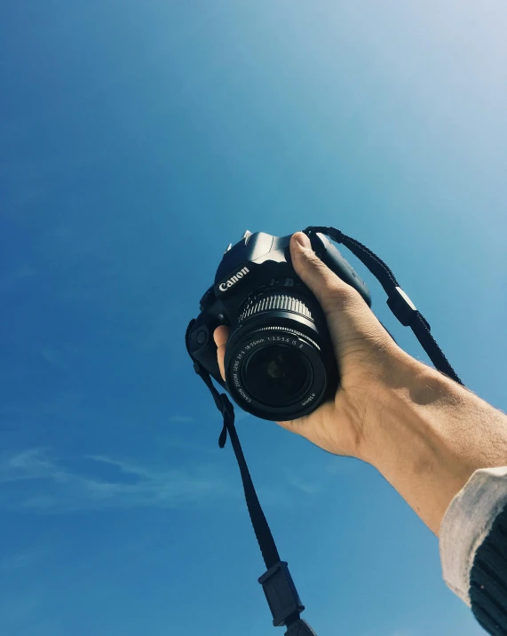 a person taking a picture with a camera, clear blue skies, holding it out to the camera, trending photo, photography]