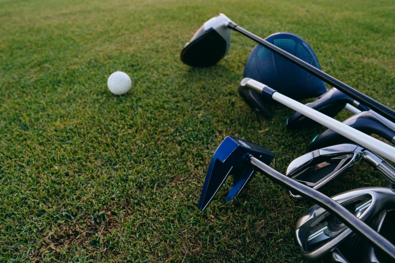 a group of golf clubs sitting on top of a lush green field, profile image, helmet view, scattered props, high quality product image”