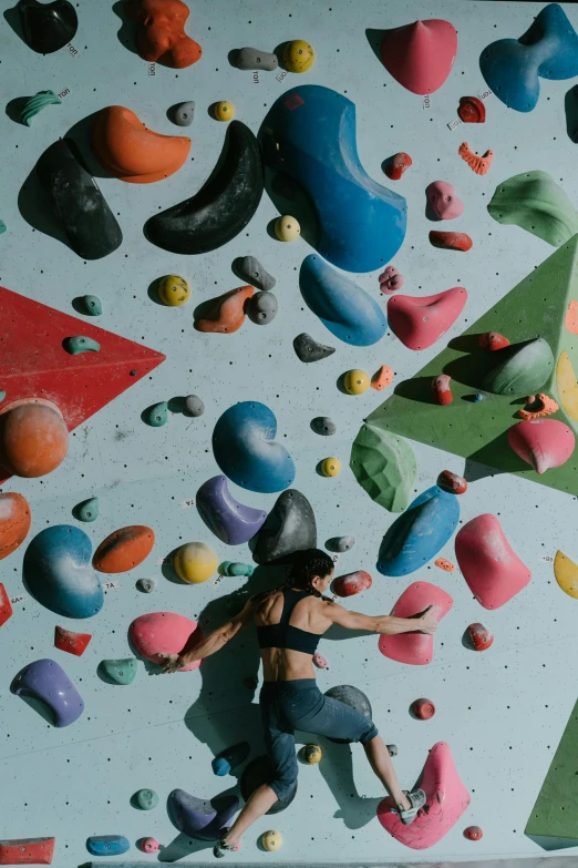 a woman standing in front of a climbing wall, unsplash contest winner, process art, floating spheres and shapes, overhead view, ((rocks)), sport