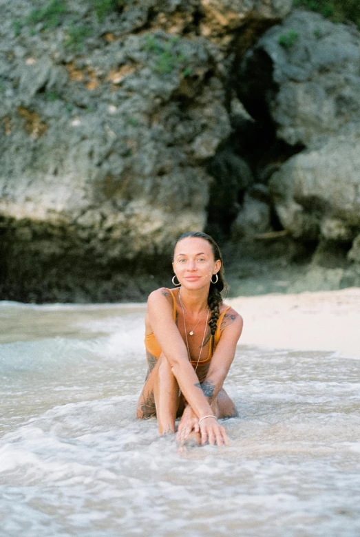 a woman sitting on top of a sandy beach, in the water, megan fox, one single tribe member, jamaica