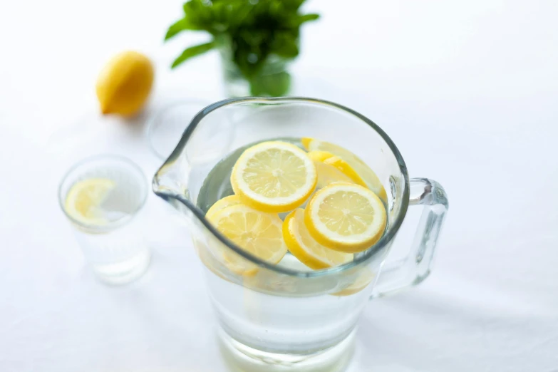 a pitcher filled with lemons sitting on top of a table, pexels, white water, 8l, full product shot, unedited