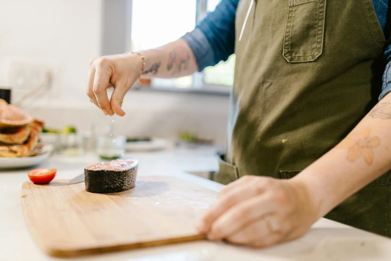 a close up of a person cutting food on a cutting board, inspired by Gordon Browne, purple mullet, looking towards camera, dwell, white apron