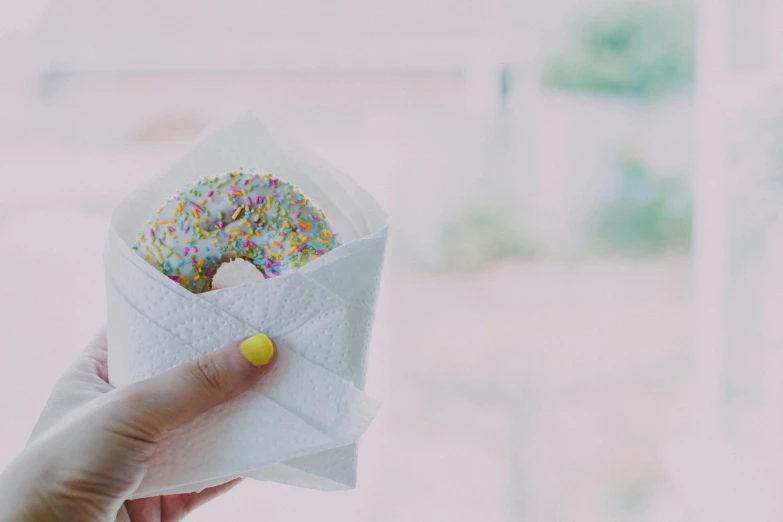 a hand holding a donut covered in sprinkles, pexels contest winner, minimalism, paper origami, white apron, 🦩🪐🐞👩🏻🦳, beautifully daylight