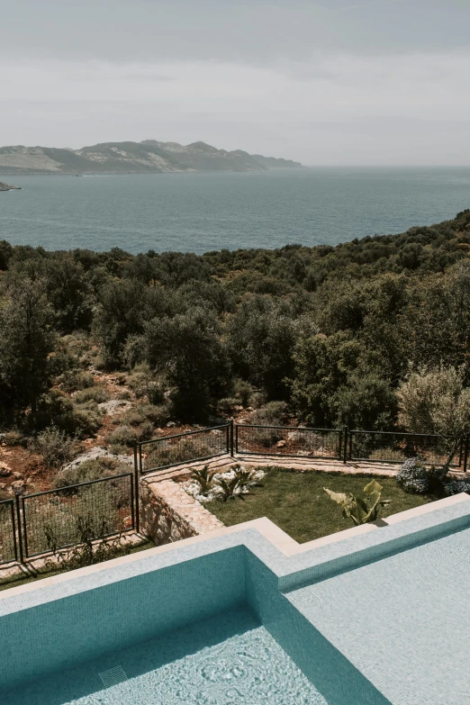 a swimming pool sitting next to a lush green hillside, inspired by Carlo Randanini, croatian coastline, turkey, from the distance, shot from roofline