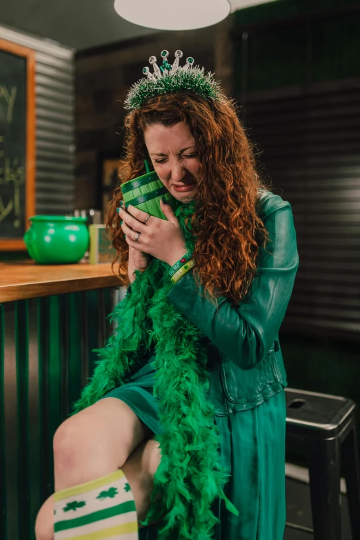 a woman in a green dress sitting on a stool, obviously drunk, irish genes, feather boa, feeling miserable