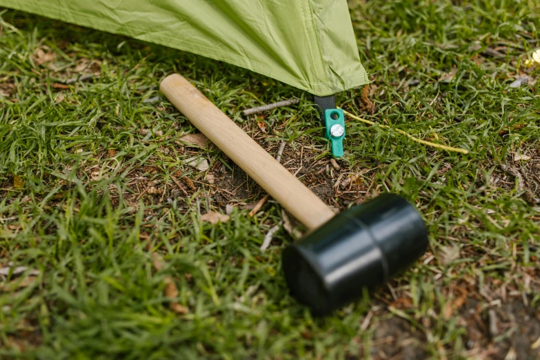 a hammer laying on the ground next to a tent, by Paul Bird, bamboo, product design shot, emerald, quest marker