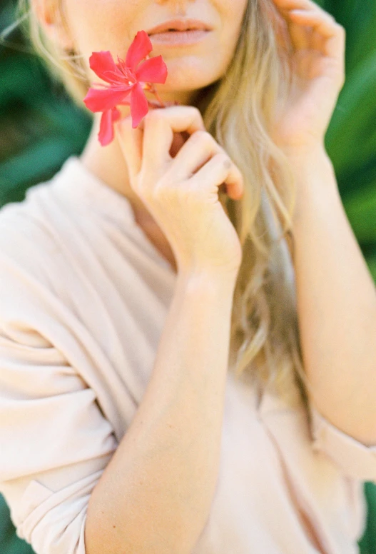 a woman holding a red flower in front of her face, by Sara Saftleven, romanticism, pink shirt, holding a bow, soft hair. light color palate, photoshoot for skincare brand