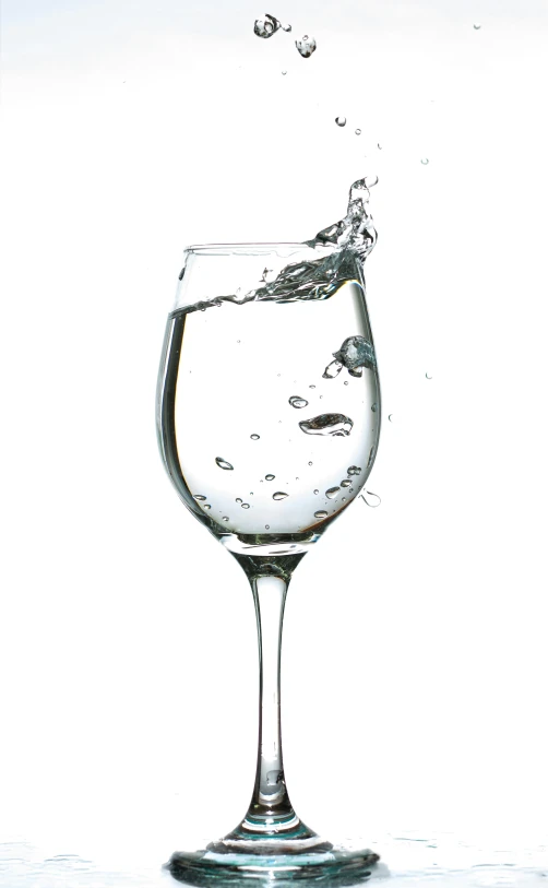 a glass filled with water sitting on top of a table, a digital rendering, by Paul Davis, pexels, renaissance, set against a white background, wineglass, splashing, short spout