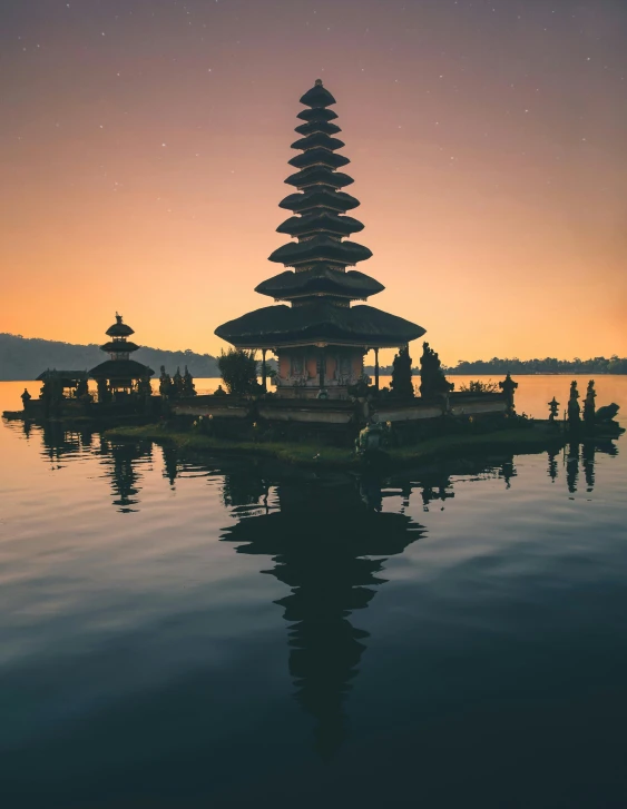 a group of people standing on top of a body of water, a temple, with a sunset