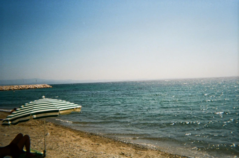 a couple of umbrellas sitting on top of a sandy beach, a picture, les nabis, small dock, 90s photo, byzantine, 2000s photo