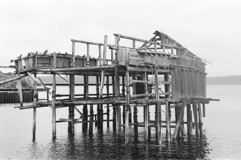 a wooden structure sitting on top of a body of water, a black and white photo, under repairs, high detail photo, fishing village, 1980s photo