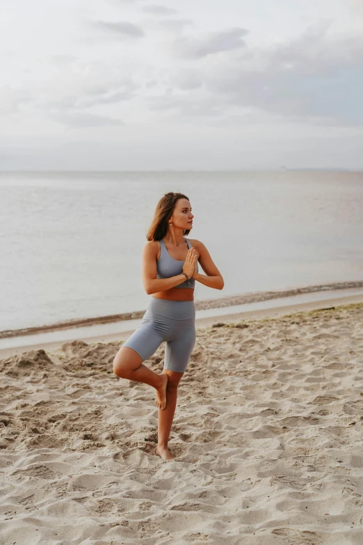 a woman is practicing yoga on the beach, unsplash, slide show, sculpted, knee, dasha taran