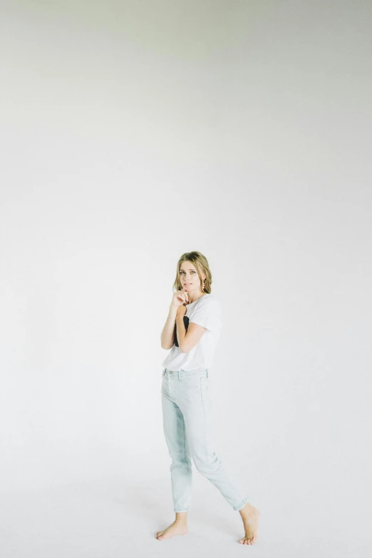 a woman walking and talking on a cell phone, by Sara Saftleven, happening, light grey backdrop, white shirt and jeans, sydney sweeney, pointé pose;pursed lips