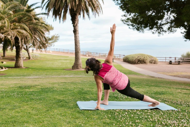 a woman doing a yoga pose in a park, a picture, by Carey Morris, unsplash, seaview, botanic garden, exterior shot, jen atkin