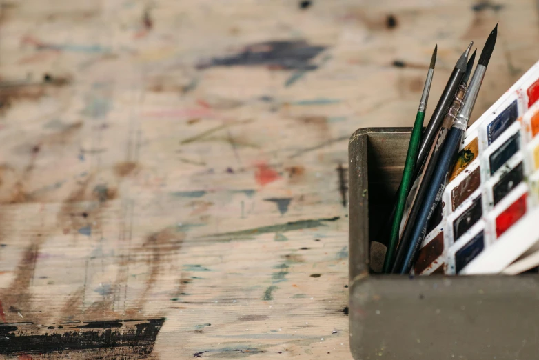 a box of paint brushes sitting on top of a wooden table, trending on pexels, arbeitsrat für kunst, antoni tapies, animation still, banner, single portrait