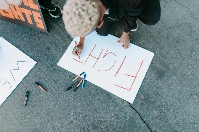 a person is writing on a piece of paper, by Julia Pishtar, pexels contest winner, graffiti, protesters holding placards, heron preston, concrete poetry, 15081959 21121991 01012000 4k