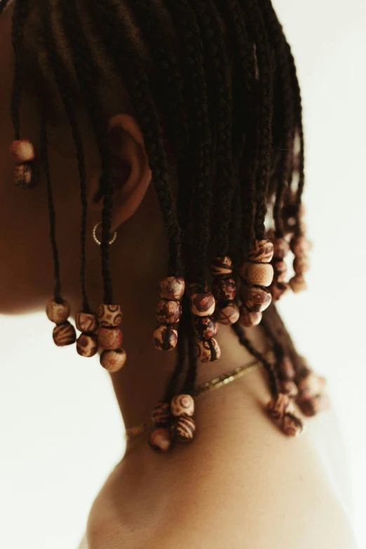 a close up of a person with dreadlocks, by Nina Hamnett, afrofuturism, wearing a dress made of beads, braided brown hair, earring, shells