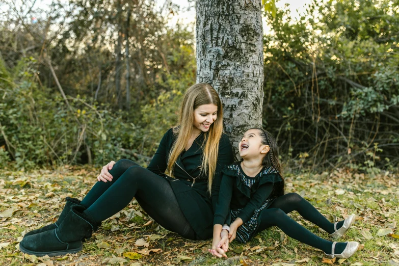 a mother and daughter sitting under a tree laughing, a portrait, unsplash, black, portrait image, full frame image, brittney lee