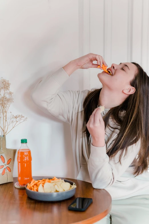 a woman sitting at a table eating food, orange theme, profile image, crisps, playful vibe