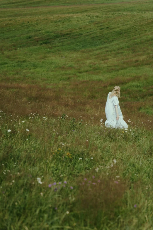 a woman in a white dress walking through a field, inspired by Andrew Wyeth, unsplash, renaissance, b - roll, faroe, ignant, meadow flowers