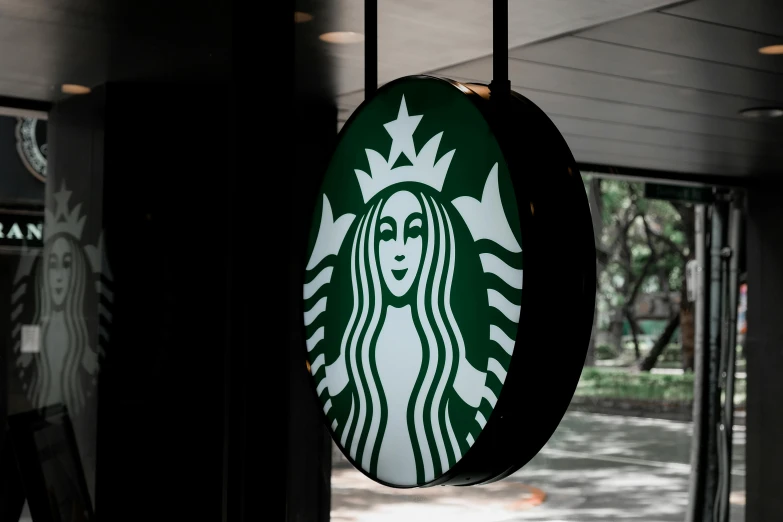 a starbucks sign hanging from the side of a building, trending on unsplash, 15081959 21121991 01012000 4k, close - up portrait shot, back lit, round-cropped