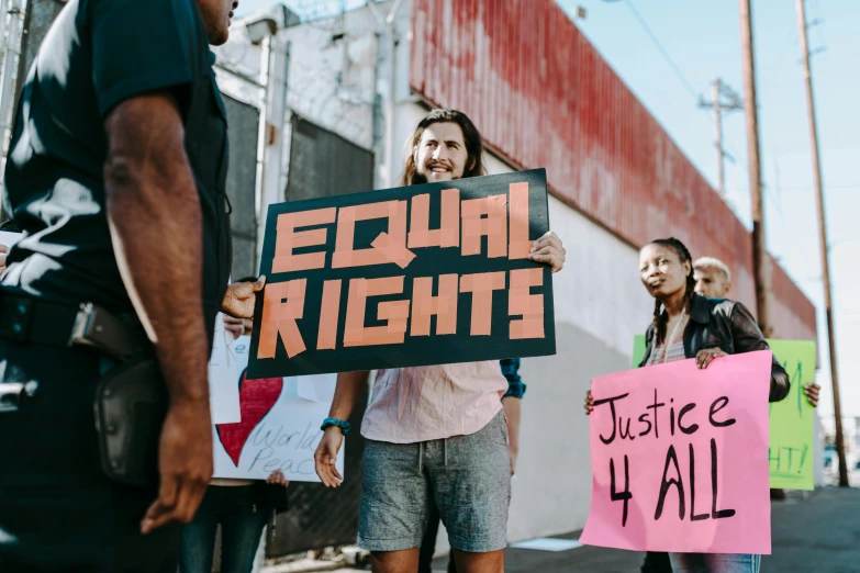 a group of people holding signs in front of a building, by Julia Pishtar, trending on pexels, feminist art, man standing, justice, brught tones, 4 0 9 6