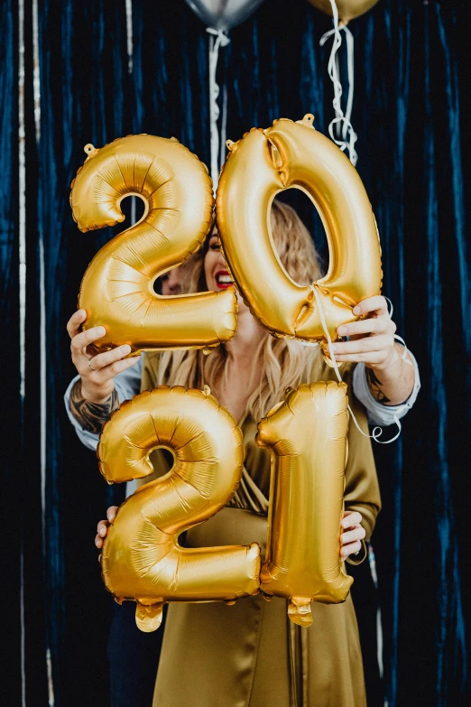 a man and woman holding up balloons that say 2013, by Julia Pishtar, trending on pexels, happening, holding a gold bag, age 2 0, sydney sweeney, decorations