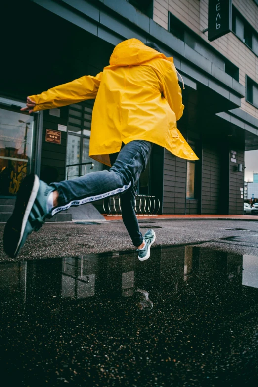 a person jumping in the air in front of a building, unsplash contest winner, hyperrealism, yellow raincoat, duck shoes, wearing adidas clothing, wet relections