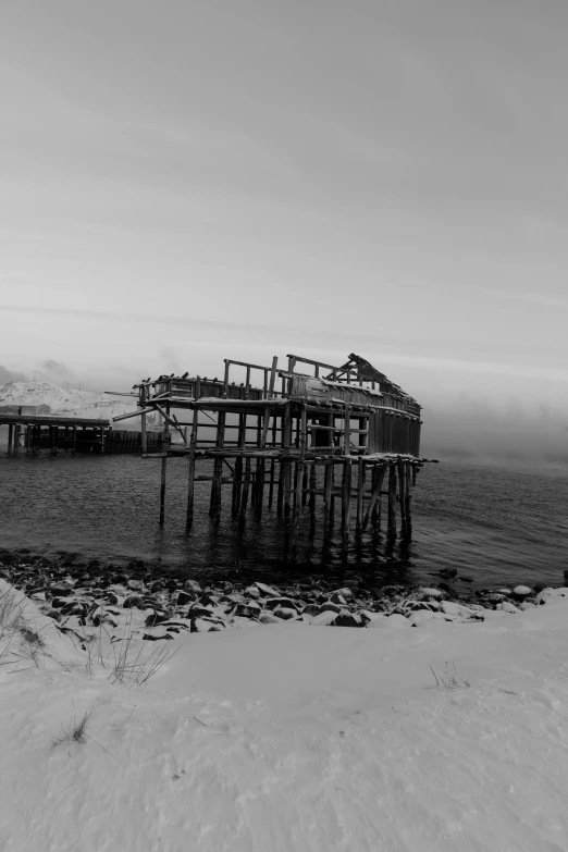 a black and white photo of a pier in the snow, by Altichiero, under repairs, burnt, fjords, fog!!!