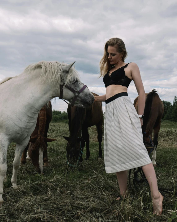 a woman standing next to a white horse in a field, by Emma Andijewska, trending on unsplash, wearing a tanktop and skirt, non binary model, wearing bra, slavic style