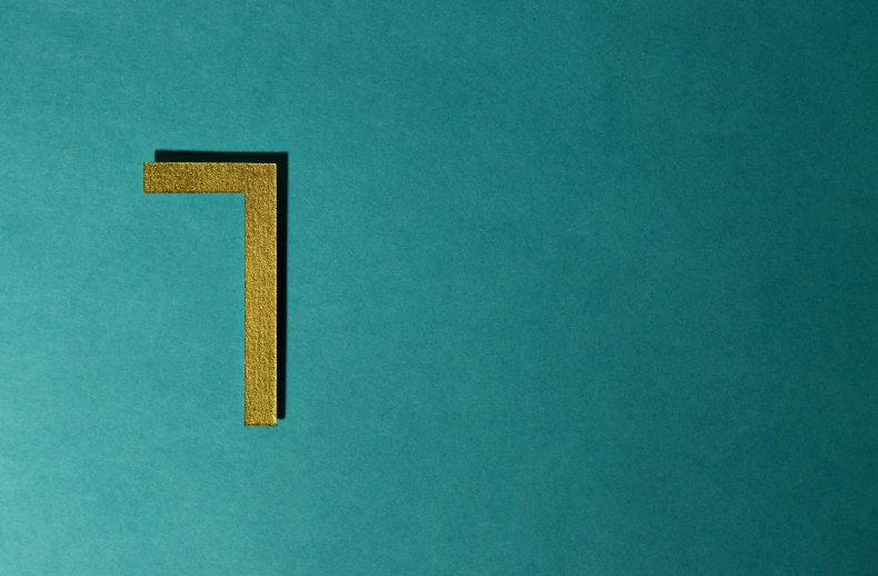 a wooden letter t on a blue background, an album cover, inspired by Josef Albers, pexels contest winner, letterism, golden number, 7, teal paper, n-4