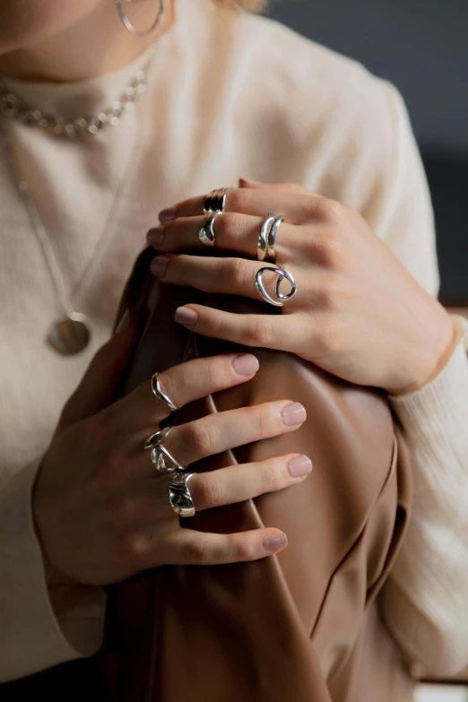 a close up of a person holding a purse, inspired by L. A. Ring, silver jewellery, smooth shapes, 2 0, beige