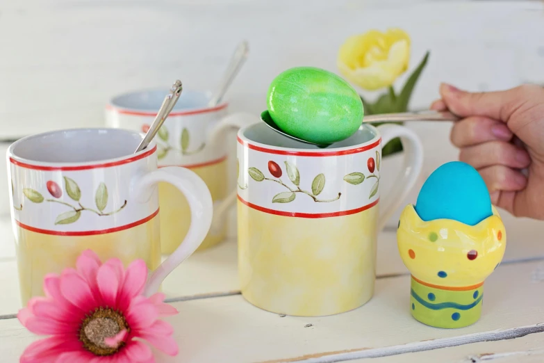 a close up of a person holding a spoon, easter, next to a cup, yellow, modelling