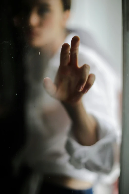 a close up of a person making a peace sign, a picture, inspired by Elsa Bleda, pexels, romanticism, boy staring at the window, crying and reaching with her arm, ghostly, woman crying