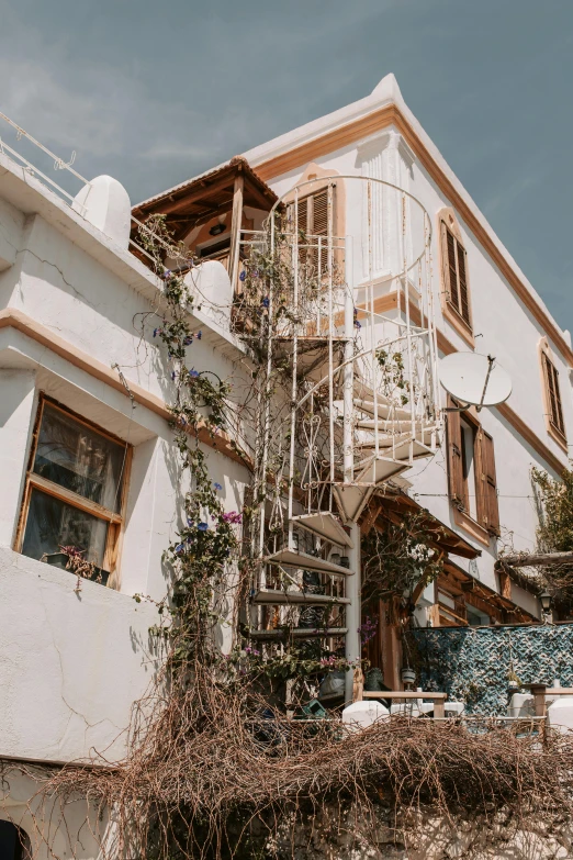 a white building with a spiral staircase in front of it, pexels contest winner, art nouveau, backyard, boho, low quality photo, moroccan